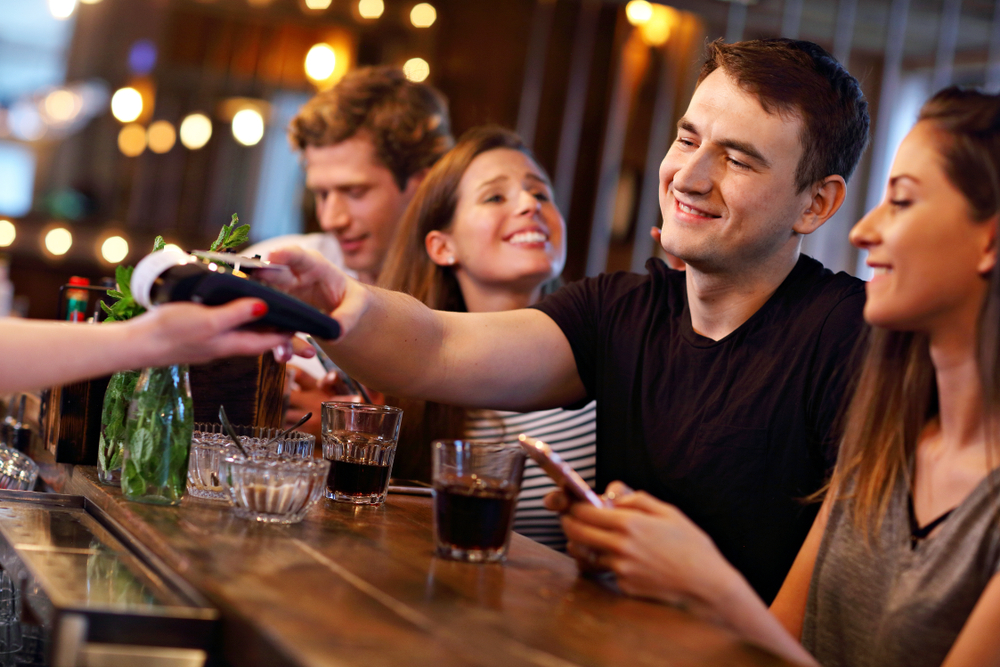 Man paying bill at a bar - 5 Key Features You Need For Your Bar POS System